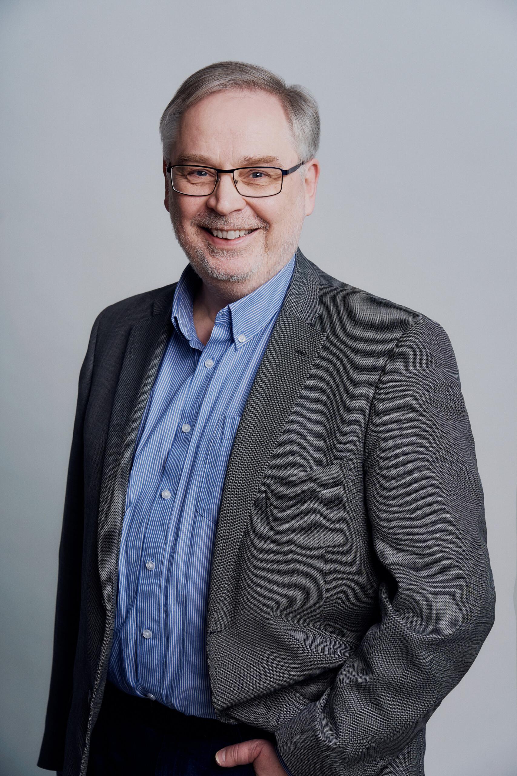 Vanhempi henkilö harmaassa puvuntakissa ja sinisessä kauluspaidassa. Projektipäällikkö Mika Holmström.